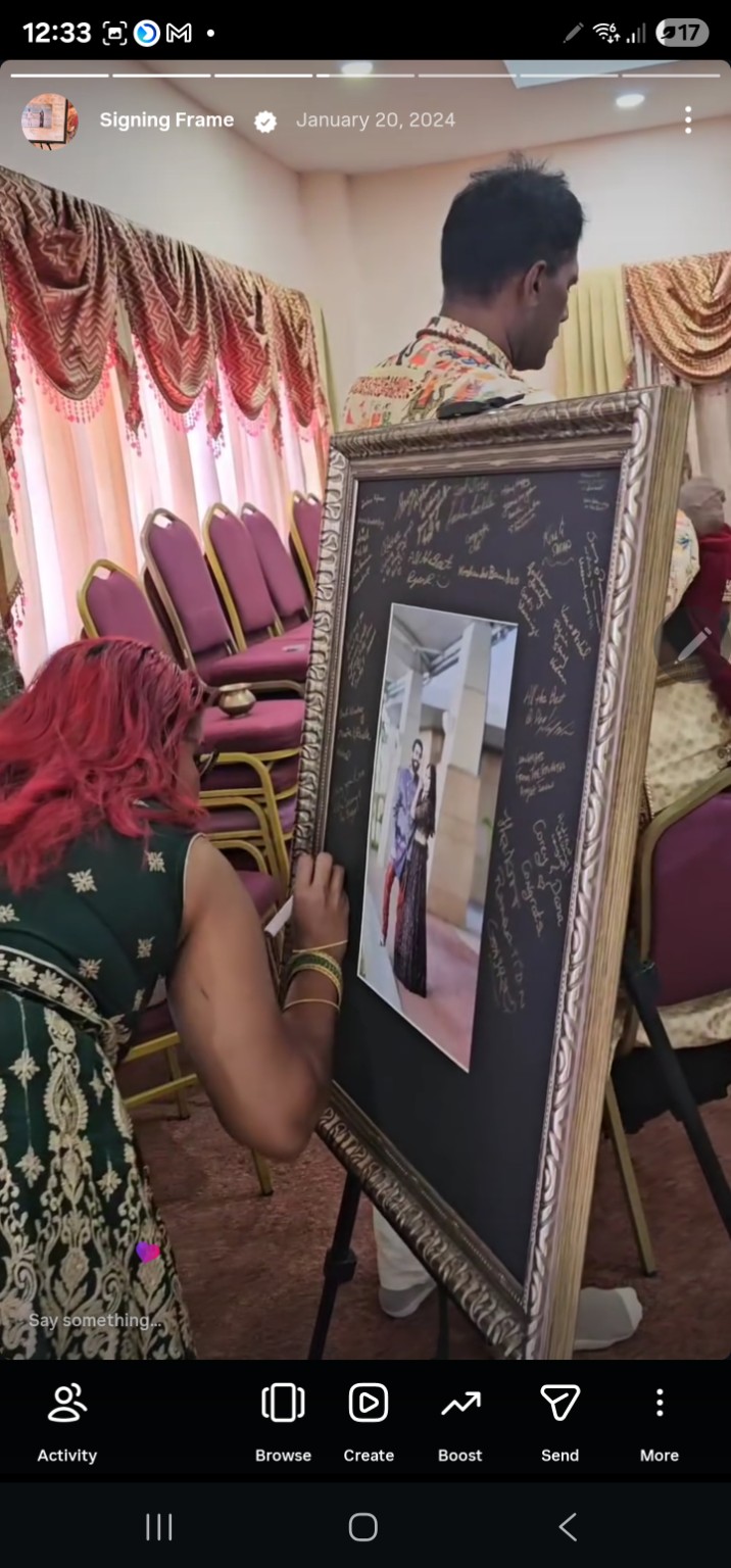 Wedding guest adding a message to a dark signing border